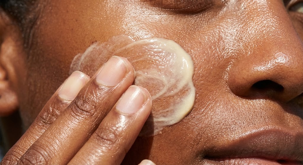 Person applying broad-spectrum sunscreen to protect against dark spots